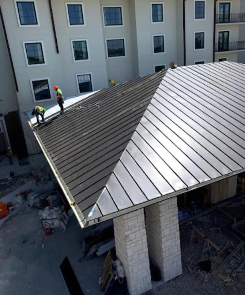 Crew installing standing seam metal roof panels on a commercial project in Clayton